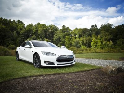 a white Tesla vehicle with trees in the background