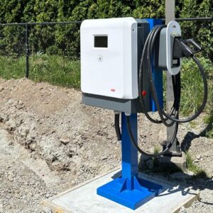 A newly installed white ev charger is mounted on a blue stand with a thick black cable and plug in Vancouver