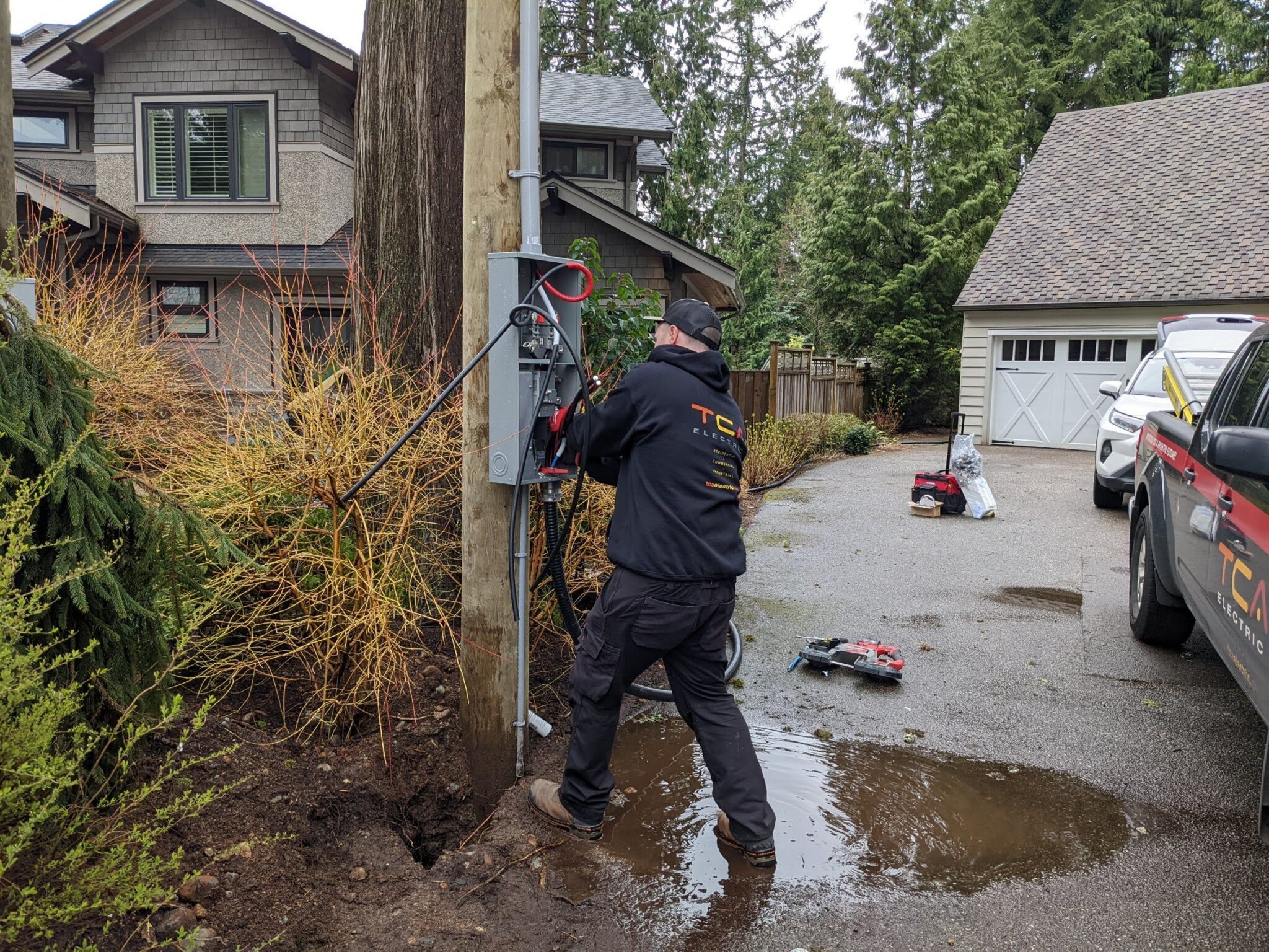 An electrician installing new outdoor service equipment on a utility pole while explaining what is involved in upgrading to 200 amp service in North Vancouver by TCA Electric.