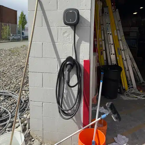 Wall-mounted commercial EV charging station with charging cable neatly coiled by TCA Electric