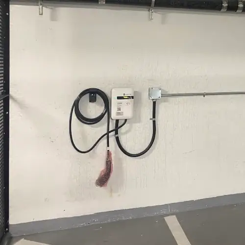 SWTCH Canadian-made EV charger securely mounted on a white concrete wall in North Vancouver multifamily parking garage, installed by TCA Electric