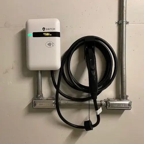 SWTCH Canadian-made EV charger mounted on garage wall with coiled charging cable, professionally installed in North Vancouver by TCA Electric