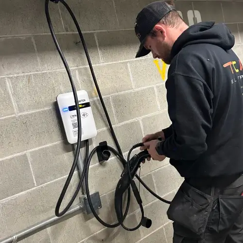 TCA Electric technician expertly setting up a SWTCH Level 2 Canadian-made EV charging station on a concrete wall in a North Vancouver parking garage