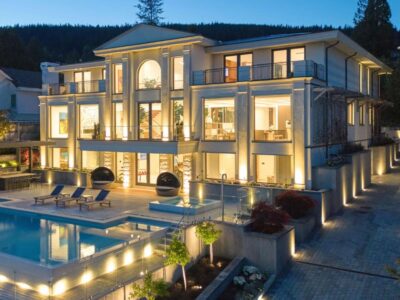 High‑end residential electrical installation West Vancouver highlighting illuminated modern mansion with glass windows, pool, and landscaped patio.