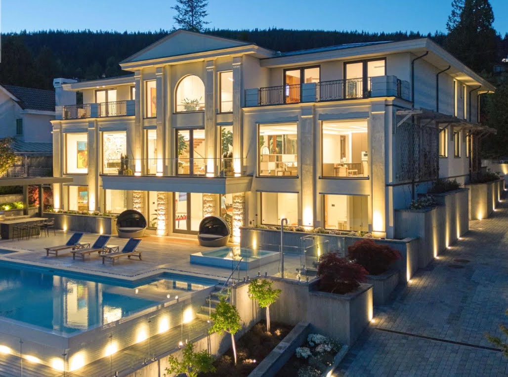 High‑end residential electrical installation West Vancouver highlighting illuminated modern mansion with glass windows, pool, and landscaped patio.