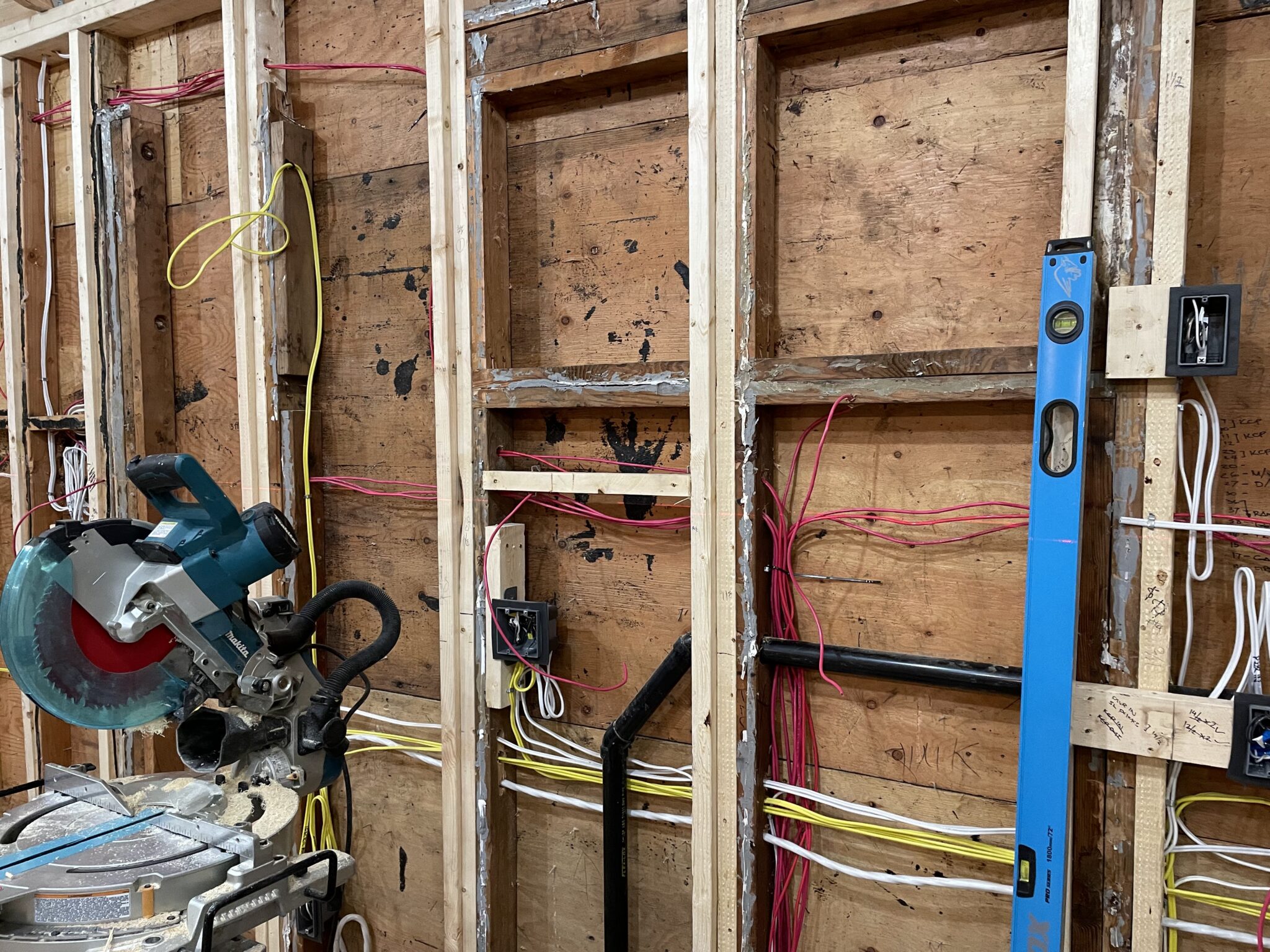 New electrical wiring and junction boxes installed behind exposed wood wall framing during a basement suite electrical renovation in North Vancouver by TCA Electric.